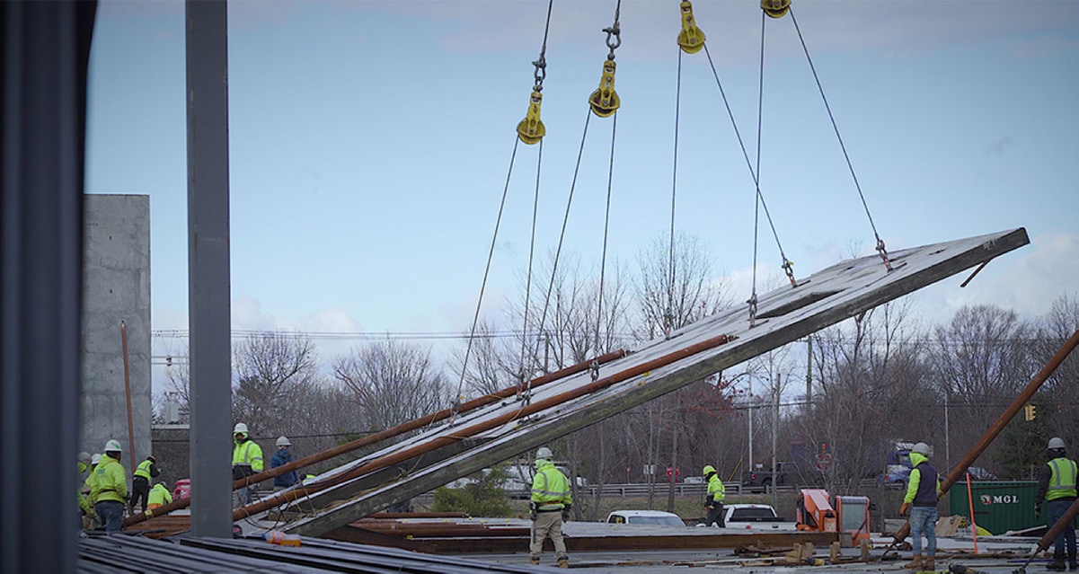 A tilt-wall being erected by a crane